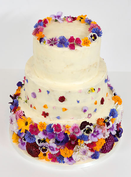 A 'Colour Burst' of Fresh Edible Wild Summer Flowers, covering a Buttercream Iced Wedding Cake, Topped with a Crown.